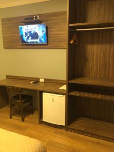 a room with a desk and a tv on a wall at HOTEL ROYAL AMAMBAI in Amambaí