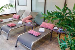 a row of benches with pillows in a room with plants at Best Western Les Bains Hotel et SPA in Perros-Guirec