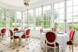 uma sala de jantar com mesas, cadeiras e janelas em Chateau de Moison, Domaine Eco Nature em Ivoy-le-Pré