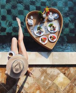 a woman laying on a table with a tray of food by a pool at Villa D'Uma in Ubud