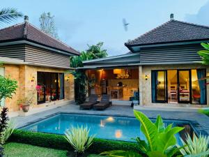 a villa with a swimming pool in front of a house at Villa D'Uma in Ubud