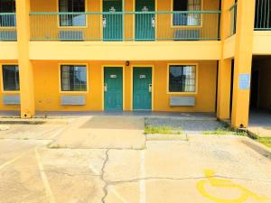 ein Gebäude mit zwei grünen Türen auf einem Parkplatz in der Unterkunft Pine Point Inn & Suites in Smithville
