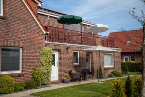 a brick house with a balcony and two umbrellas at Friesenstraße 13 in Bensersiel