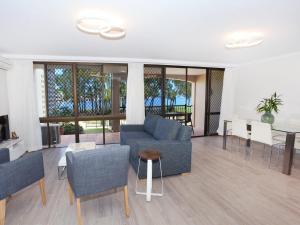 sala de estar con sofá azul y sillas en 2 bedroom Apt on Parkyn Parade with pool and Airvconditioning, en Mooloolaba