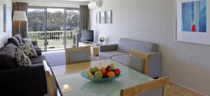 a living room with a table with a bowl of fruit on it at Main Beach Apartments in Byron Bay