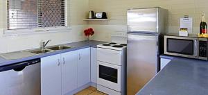 a kitchen with a stove, refrigerator, microwave and sink at Main Beach Apartments in Byron Bay