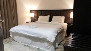 a bedroom with a large bed with white sheets at Najran Hotel in Najran