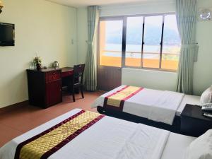 una camera d'albergo con due letti, una scrivania e una finestra di Khách sạn Bình Dương a Quy Nhon Altre 62 foto