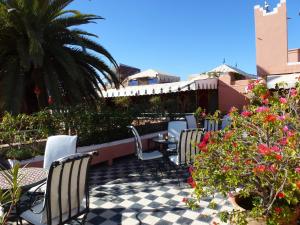 un patio avec des chaises, une table et des fleurs dans l'établissement Hotel Le Gallia, à Marrakech
