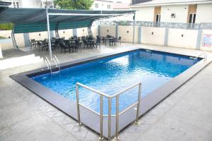 a swimming pool in a patio with tables and chairs at Lit Suites in Abuja