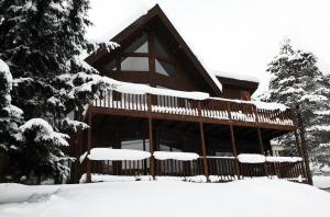domek z bali na śniegu z drzewami pokrytymi śniegiem w obiekcie Furano Lodge 10 w mieście Furano
