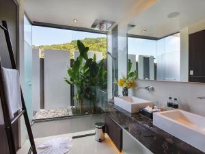 a bathroom with a sink and a large mirror at Villa Saan - SHA Extra Plus in Kamala Beach