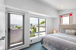 a bedroom with a bed and two windows at TrinketBox in Wellington