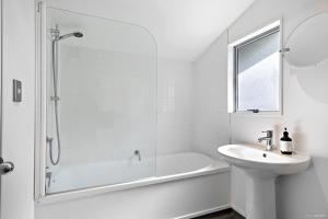 a white bathroom with a tub and a sink at TrinketBox in Wellington