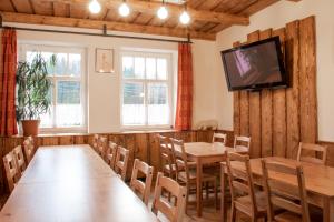 a dining room with tables and chairs and a flat screen tv at Penzion Medvídek Tanvald in Tanvald