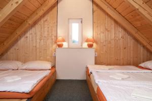 two beds in a room with wooden walls at Penzion Medvídek Tanvald in Tanvald