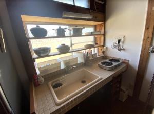 eine Küche mit Spüle und einigen Töpfen und Pfannen in der Unterkunft KOME HOME in Tōkamachi
