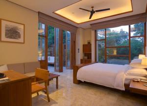 ein Schlafzimmer mit einem Bett und einem Schreibtisch sowie ein Zimmer mit einem Fenster in der Unterkunft Bolian Resorts & SPA Chongqing in Chongqing