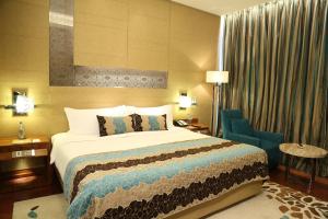 a hotel room with a bed and a blue chair at Taj City Centre Gurugram in Gurgaon