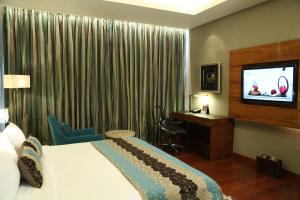 a hotel room with a bed and a flat screen tv at Taj City Centre Gurugram in Gurgaon