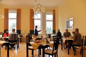 a group of people sitting at tables in a restaurant at Hotel Villa Ponte Wisera in Eschwege