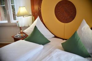 Habitación de hotel con cama con almohadas verdes y blancas en Hotel Villa Ponte Wisera, en Eschwege