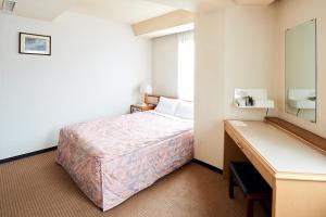 
a hotel room with a bed and a desk at Marroad Inn Tokyo in Fuchu
