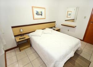 a bedroom with a large white bed and a night stand at Solar Flat Hotel in Juiz de Fora