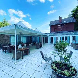 a patio with tables and chairs and a building at Villa Waldesruh in Siegburg