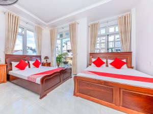 2 bedden in een slaapkamer met rode kussens bij OYO 446 The Bao Hotel in Da Lat