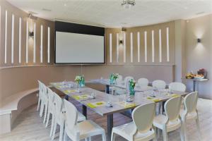 a conference room with a long table and white chairs at Logis L'Auberge de Larressingle in Larressingle