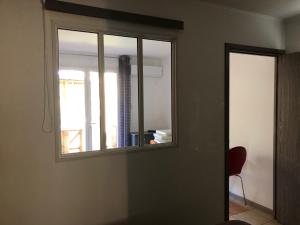 een kamer met een raam en een rode stoel bij Résidence les Caraibes in Sérignan