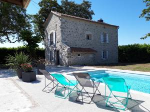 een villa met een zwembad en 2 stoelen en een gebouw bij Gîte des Magnolias in Nérac