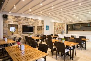 a restaurant with wooden tables and chairs and a stone wall at Datca Beyaz Ev Hotel in Datca