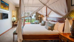 a bedroom with a canopy bed and a desk at Avani Pemba Beach Hotel in Pemba