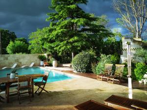 een zwembad met stoelen en een tafel en een tafel en een tafelblad bij Mas D'Ange en Provence in Les Taillades
