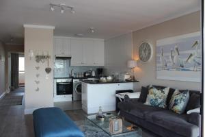 a living room with a couch and a kitchen at Waterfront - Knysna Quays Accommodation in Knysna