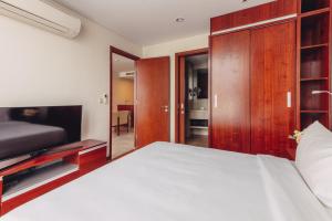 a bedroom with a large white bed and a tv at SILA Urban Living in Ho Chi Minh City