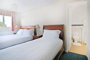 a bedroom with two beds and a bathroom with a sink at Virginia Lodge in Stratford-upon-Avon