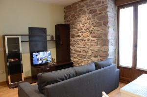 Una sala de estar con un sofá y una pared de piedra. en Apartamentos Elizondo, en Elizondo