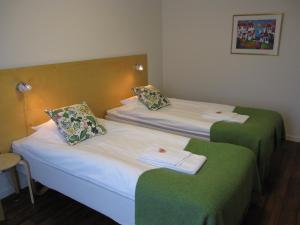 2 camas en una habitación con verde y blanco en Hotell Ramudden en Gävle