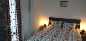 1 cama en un dormitorio con 2 lámparas y colcha en Căsuța Noastra, en Bucarest
