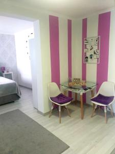 Schlafzimmer mit lila Stühlen und einem Glastisch in der Unterkunft Studio AJDY in Mostar