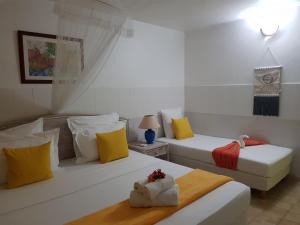 2 camas en una habitación de color amarillo y blanco en ROY'AL BEACH HOLIDAYS, en Sainte-Luce