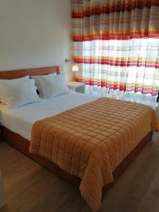 ポルトにあるBC Porto Downtown Apartmentのベッドルーム1室(オレンジ色の毛布、窓付)