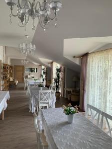 a dining room with white tables with flowers on them at Dēseles dzirnavas - Guest House in Embūte