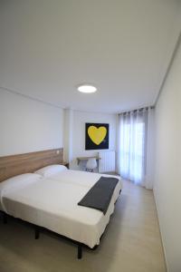 Apartamentos Gran Socaire de Noja في نوخا: غرفة نوم بسرير ابيض كبير ونافذة