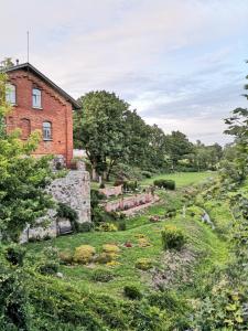 a brick house with a garden in front of it at Dēseles dzirnavas - Guest House in Embūte