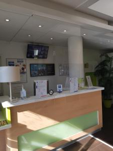 a reception desk with a green bench in a room at Ibis Budget Marseille Valentine in Marseille