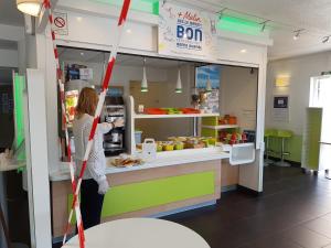 a woman standing in front of a food counter in a store at Ibis Budget Marseille Valentine in Marseille